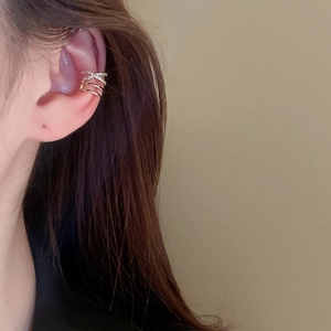 Close-up of golden multi-layer ear cuff with crisscross zircon stones on model's ear