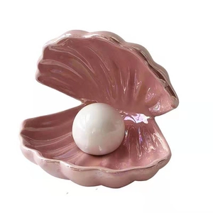 Nordic shell ceramic night light with a glowing white pearl on a clean white background