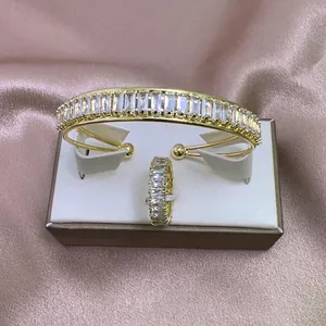 Detalle de conjunto de brazalete y anillo chapado en oro con circonitas baguette