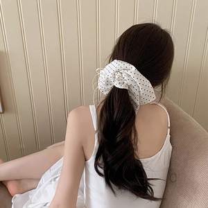 Close-up of oversized white fabric hair scrunchie with black polka dots on low ponytail