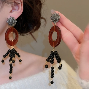 Detail of ethnic style tassel earrings with grey faceted beads and brown resin