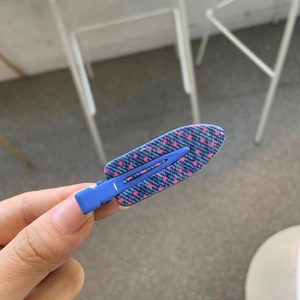 Detailed close-up of a blue duckbill hair clip with red polka dots in hand