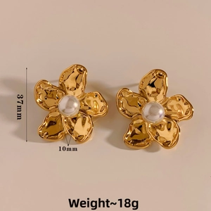 Detailed close-up of golden petal earrings with central white pearl and hammered texture