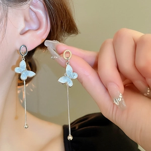 Detail of silver butterfly tassel earrings with blue faux crystal on model ear
