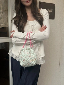 Close-up of mint green quilted drawstring bag with pink bunny and floral patterns