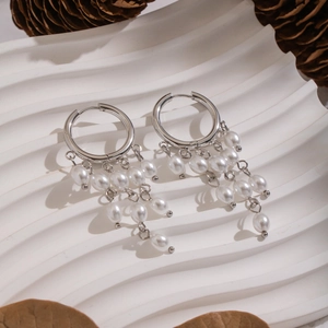 Detail of silver round hoop earrings with baroque pearl tassels on display