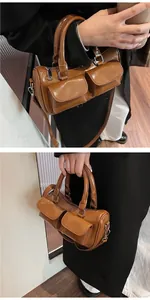Detail view of caramel brown bucket bag with dual front pockets and silver zippers