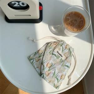 Detail of floral fabric drawstring pouch with tulips next to coffee and a retro clock