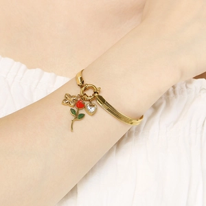 Detail of gold heart and rose enamel charms on a stainless steel tassel bracelet