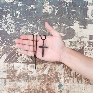 Détail d'un pendentif croix noir en acier inoxydable avec chaîne à mailles carrées