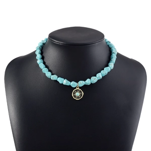 Bohemian evil eye turquoise necklace with golden sun pendant on black display stand