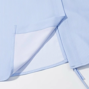 Detail of light blue pinstripe shirt hem showing precise stitching and fabric texture