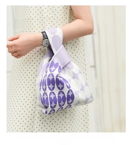 Detail of purple and white geometric knit tote bag worn by a model in a minimalist setting