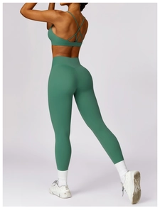 Detail showing cross-back sports bra and high-waist green yoga pants from the back