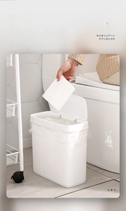 Detail of white slim trash can with a wide-press lid for narrow bathroom spaces