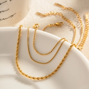 Detailed shot of layered gold rope, snake, and bead chains with lobster clasp and extender