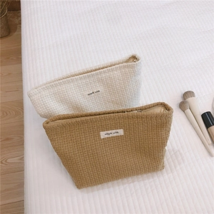 Macro detail view of woven waffle texture cosmetic bags in cream and tan beige colors
