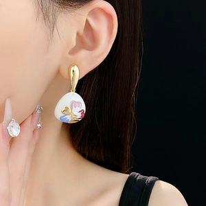 Close-up of vintage floral drop earring with colorful enamel patterns on female ear