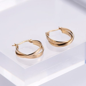 Minimalist gold plated double hoop cross earrings on transparent display stand