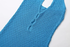 Detail of blue crochet knit dress with geometric diamond pattern and V-neckline texture