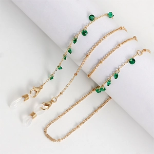 Detail view of gold glasses chain featuring green faceted stones and silicone loops
