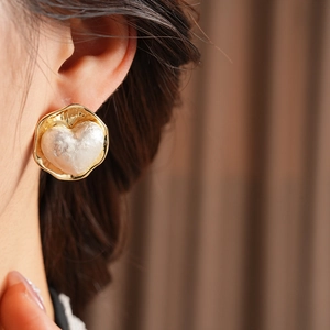 Gros plan d'un mannequin portant des boucles d'oreilles cœur dorées au fini baroque