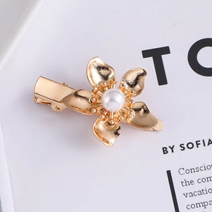 Elegant gold metal flower hair clip with pearl center on minimalist white background