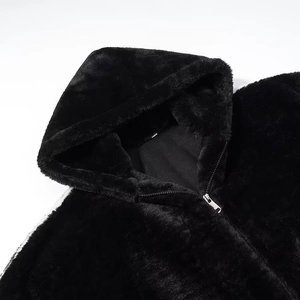 Detailed macro view of black faux fur texture and metal zipper on hooded jacket