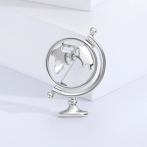 Detail showing the polished silver globe brooch with metallic texture on white background