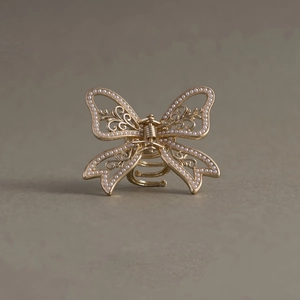 Detailed view of a gold butterfly hair claw with white pearls and hollow metal craft
