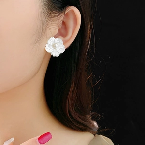 Détail de boucles d'oreilles fleur avec nacre et perle portées sur l'oreille