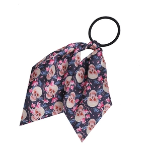 Detail of fabric hair scrunchie with pink skulls and floral pattern on black background