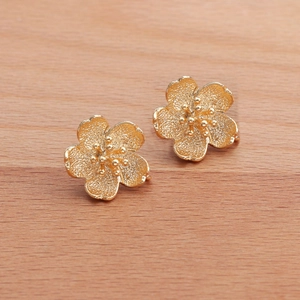 18k gold plated 3D floral leaf earrings with matte texture and polished edges on wood