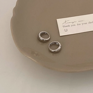 Minimalist silver hoop earrings on a decorative ceramic plate with a brand thank you card