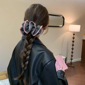 Black and white checkered hair scrunchie with pink ruffle trim worn in a ponytail