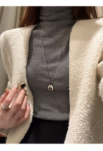 Silver drop pendant necklace on a model wearing a grey turtleneck and tweed jacket