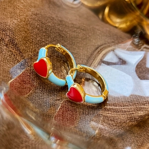 Detailaufnahme goldener Creolen mit blauer Emaille und roten Herz-Verzierungen