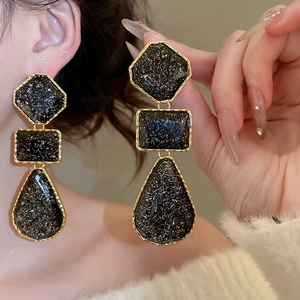 Detail of vintage resin drop earrings with gold trim and black stone texture finish