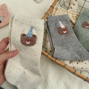 Close-up of cotton bear socks with colorful dots and embroidered party hat bear detail