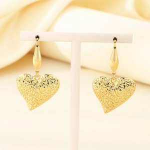 Detail of golden heart earrings with irregular texture hanging on a display stand