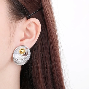 Close-up of oversized geometric oval earrings in two-tone gold and silver finish