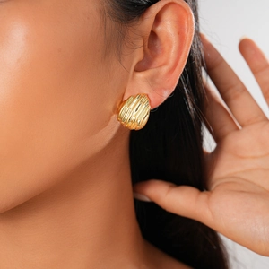 Gros plan de boucles d'oreilles dorées géométriques avec un motif de vagues vertical