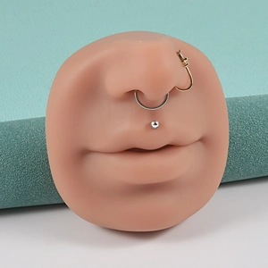Close-up of golden nose ring and silver studs on professional silicone piercing model