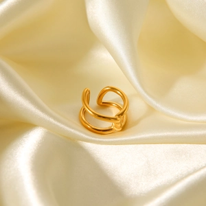 Detailed view of an 18K gold knot ring on soft champagne silk fabric background
