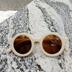 Flat lay of vintage round kids sunglasses with cream matte frames and brown lenses
