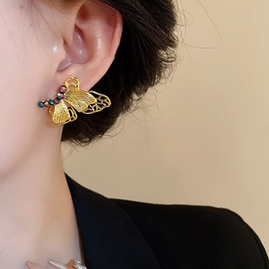 Elegant gold butterfly stud earrings with colorful beads shown on model's ear