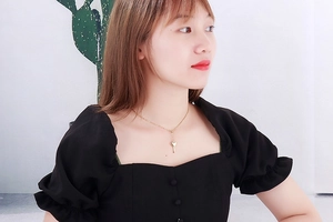 Golden stainless steel heart-shaped key pendant necklace worn on female model's neck