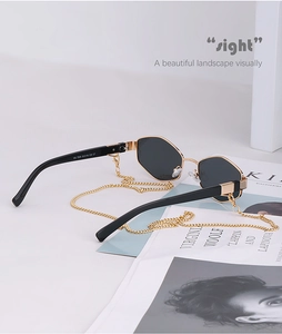 Detail of octagonal black and gold sunglasses with luxury gold metal chain strap