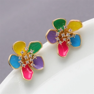 Macro shot of colorful enamel flower earrings with cubic zirconia on a white dish