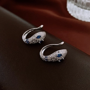 Macro shot of silver snake ear cuff with blue and white zircons on leather